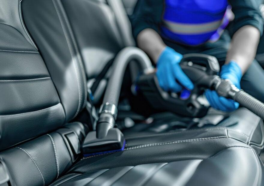 Detailer vacuuming a vehicle's interior during professional car detailing
