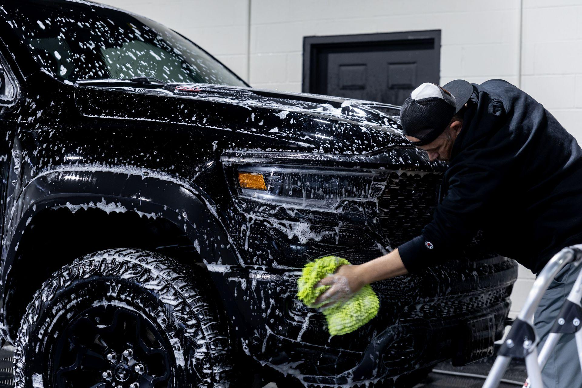 Professional hand car wash removing road grime from a black SUV in Houston